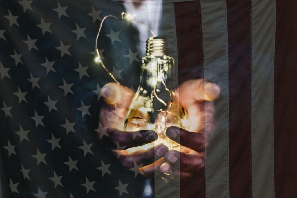 a man holding a lightbulb in front of an American flag