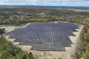 an aerial shot of a small solar farm between trees